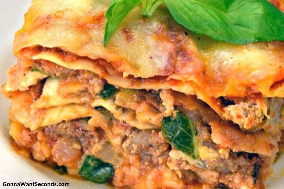 A sliced serving of crockpot lasagna topped with fresh basile, on a plate