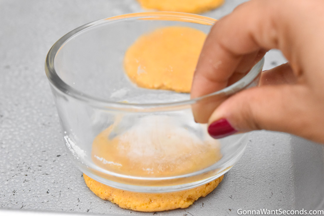 Pressing Pumpkin Sugar Cookies with a small flat glass bottom bowl