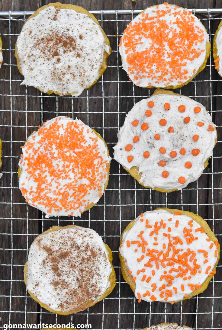 Pumpkin Sugar Cookies with frosting topped with different toppings on a wire rack