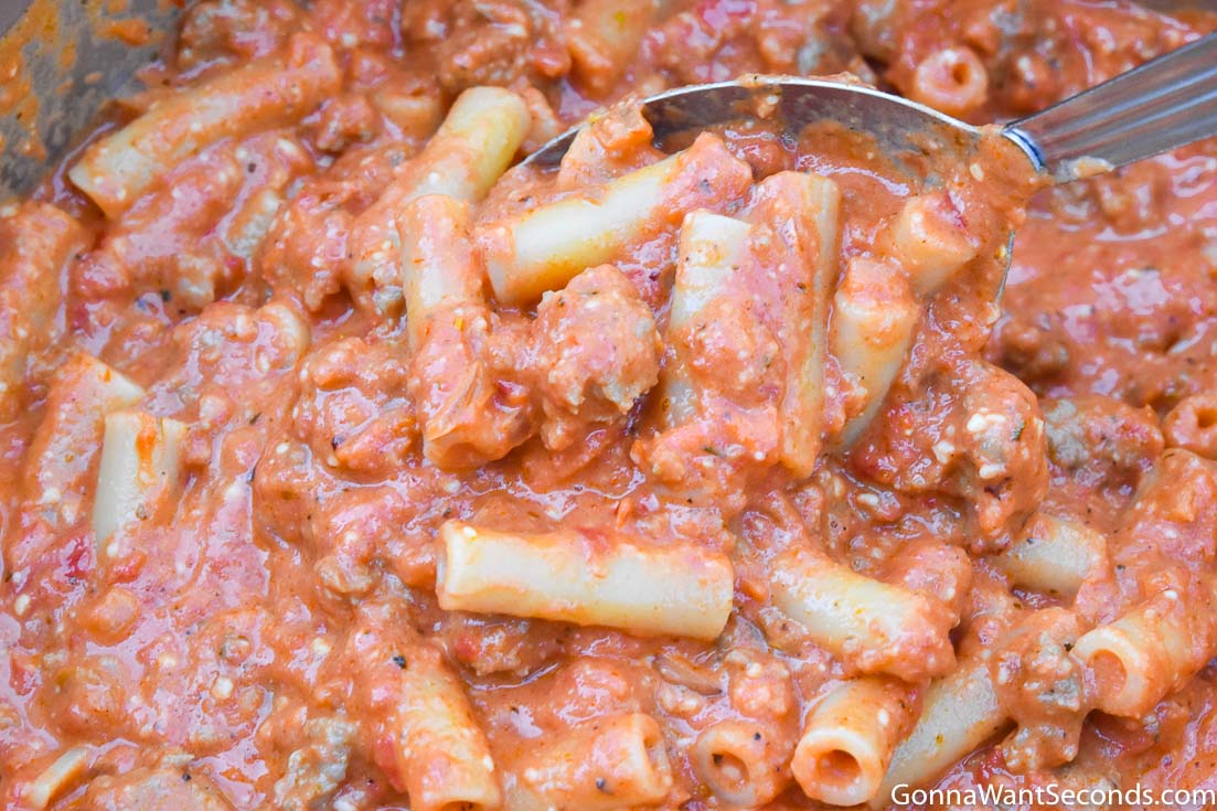step by step how to make baked ziti with sausage, scooping pasta with sauce