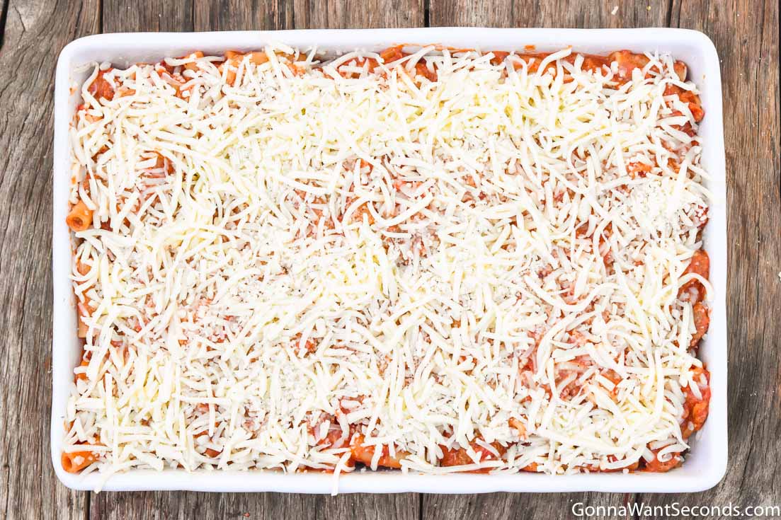 step by step how to make baked ziti with sausage, layering cheese over pasta
