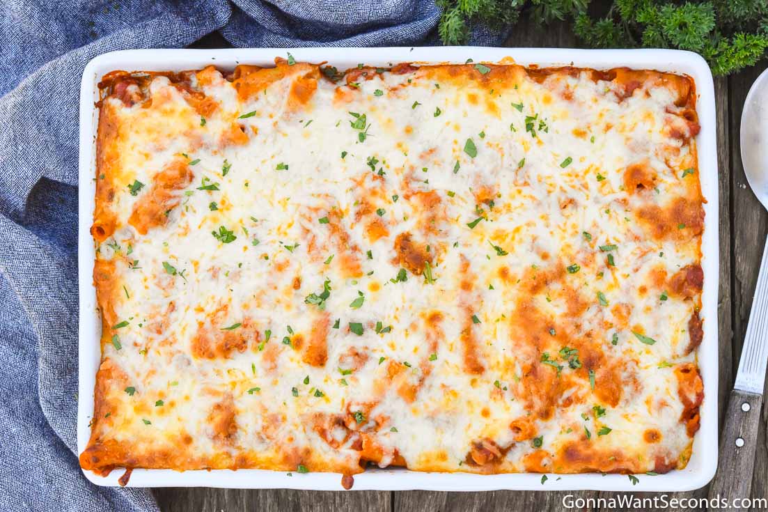 baked ziti with sausage topped with melted cheese, in a casserole dish