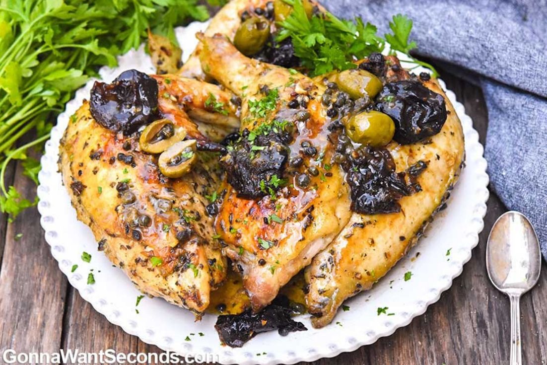 Chicken Marbella topped with capers and prunes, on a plate