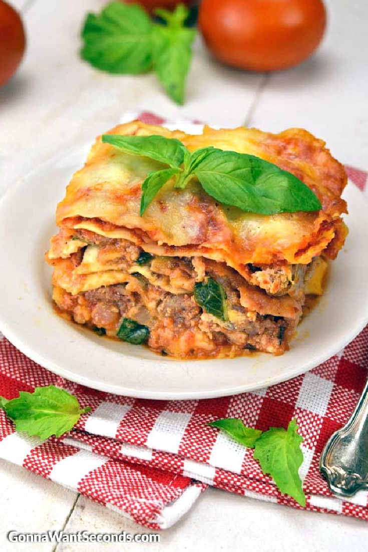 A slice crock pot lasagna topped with fresh basil, on a plate
