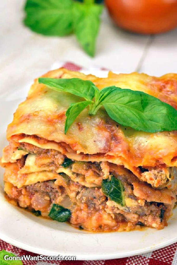 A slice of slow cooker lasagna topped with fresh basil, on a plate