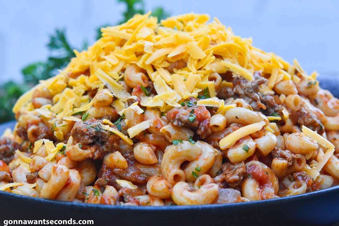 A bowl full of Hamburger Goulash, topped with shredded cheese