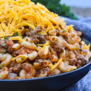 A bowl full of Hamburger Goulash, topped with shredded cheese
