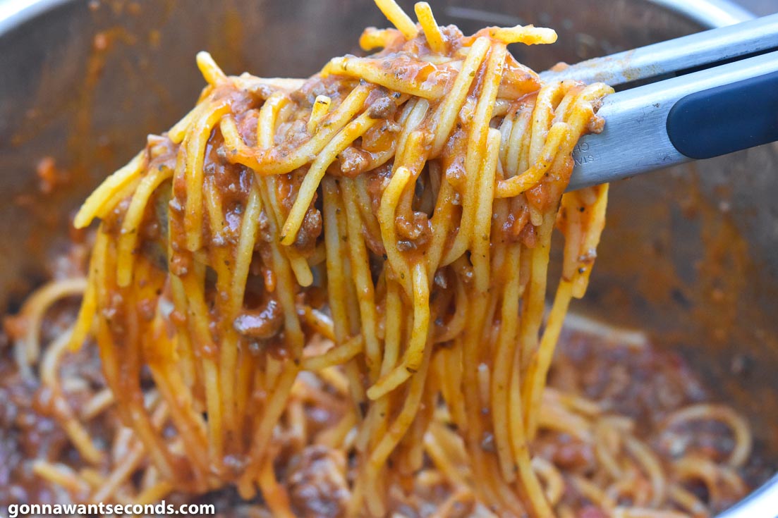 How To Make instant pot spaghetti with ground beef, Picking pasta from an instant pot with a kitchen thong