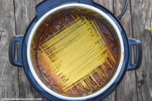 How To Make instant pot spaghetti with meat sauce, placing dry spaghetti on an instant pot with sauce
