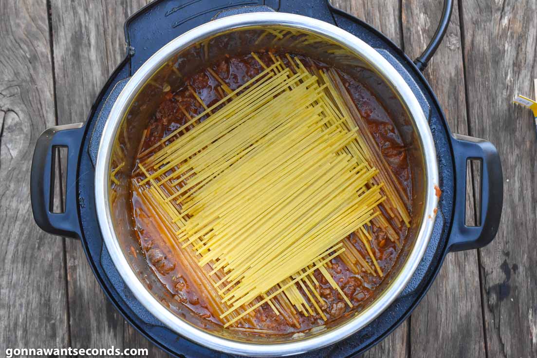 How To Make Instant Pot Spaghetti, placing dry spaghetti on an instant pot with sauce