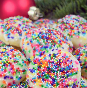 A pile of Italian Christmas Cookies, with Christmas decors at the back