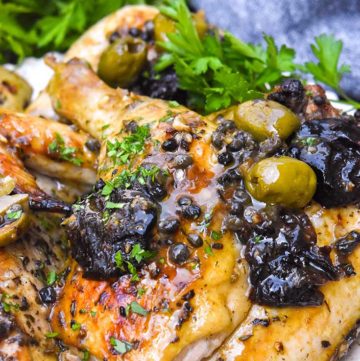 Chicken Marbella topped with capers and prunes, on a plate