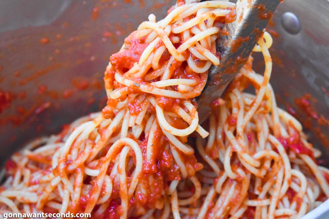 Mixing Italian spaghetti sauce and noodles in a pot 