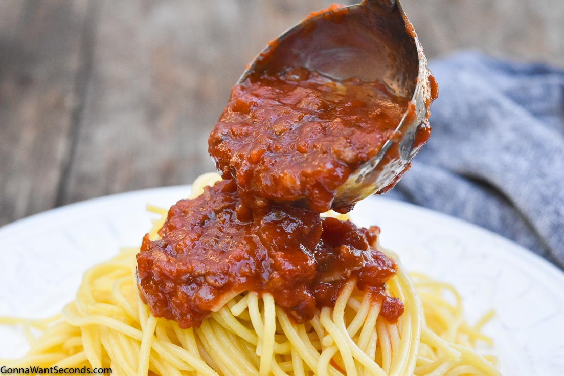 Ladle pouring Italian spaghetti sauce over spaghetti pasta