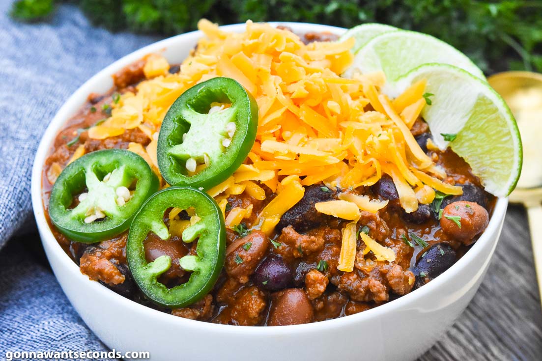 Pioneer Woman chili with masa topped with cheese, jalapeno, and lime, on a bowl