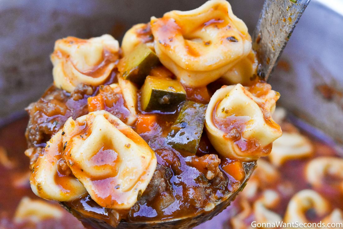Ladle scooping italian sausage tortellini soup from the pot