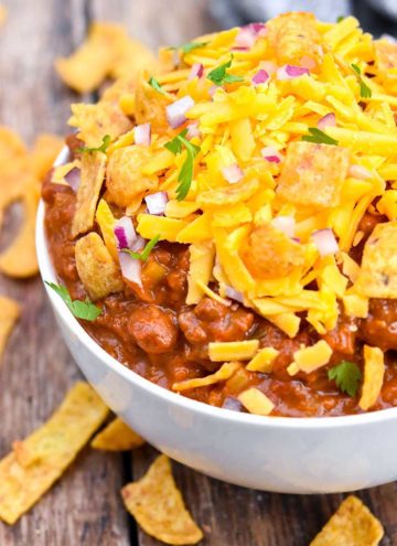 Boilermaker chili topped with shredded cheese, Fritos, and onions, in a bowl
