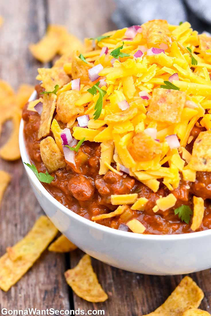 Boilermaker chili topped with shredded cheese, Fritos, and onions, in a bowl