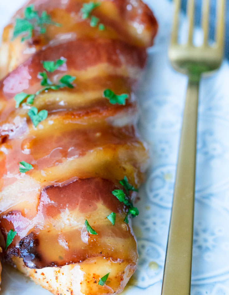 Bacon Wrapped Chicken topped with sauce, on a plate