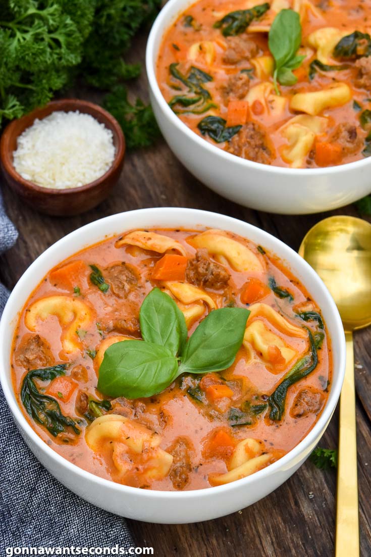 Creamy tortellini soup topped with fresh basil, in a bowl