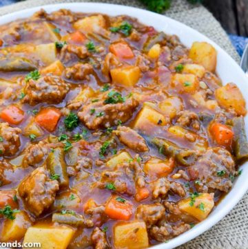 old fashioned hamburger stew in a bowl with spoon on the side