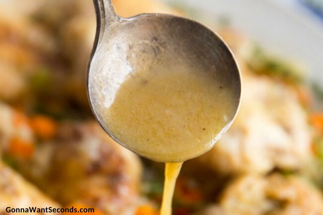 Ladle pouring gravy over smothered chicken