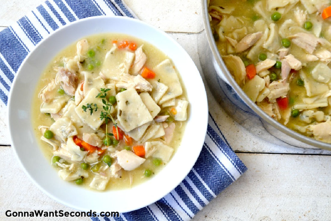 A bowl of Southern Style Chicken And Dumplings with the pot on the side