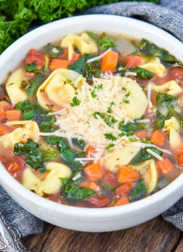 spinach tortellini soup topped with shredded parmesan cheese in a bowl