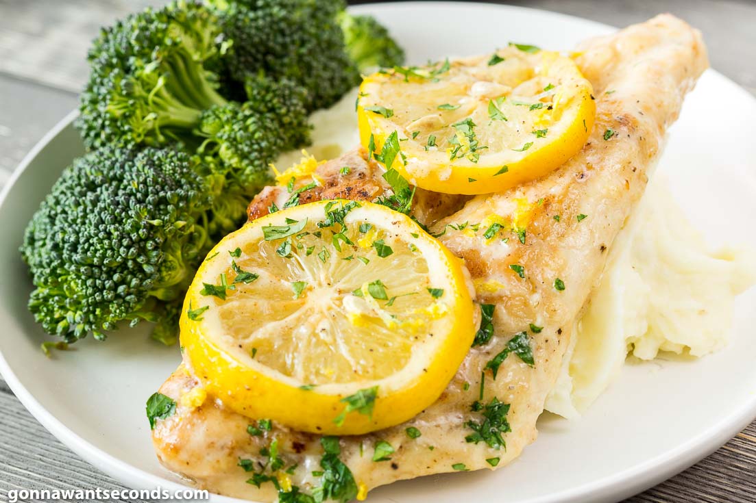 Creamy Lemon Chicken topped with sliced lemons with broccoli on the side