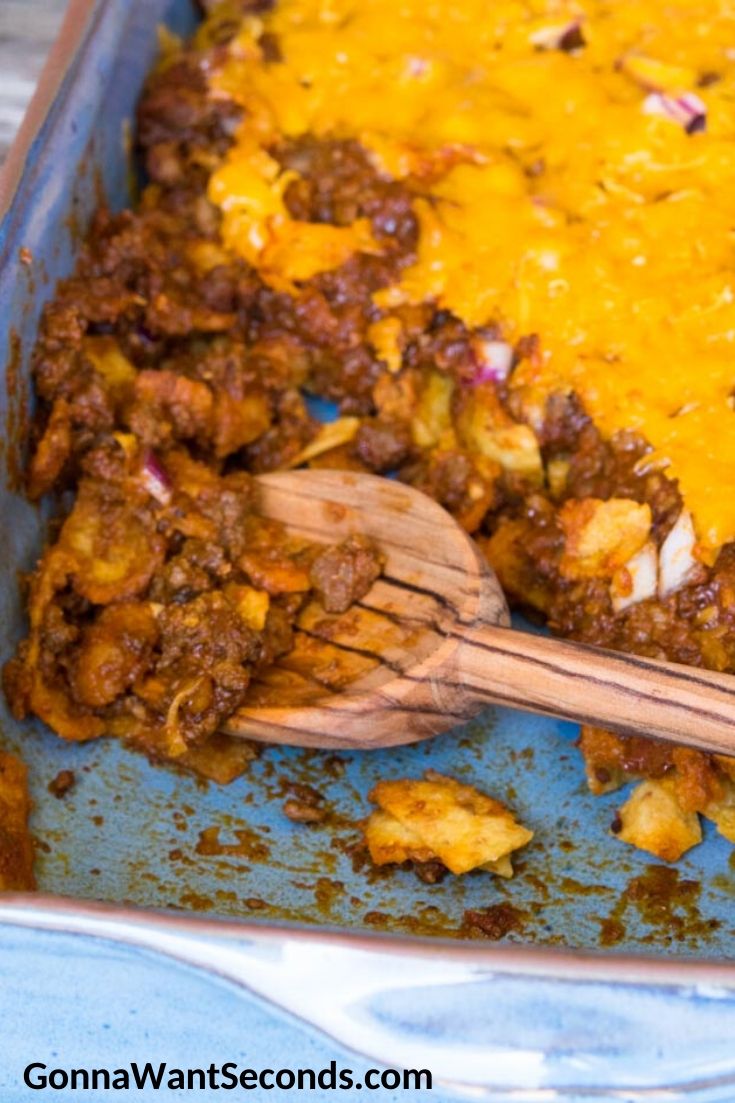 Scooping out a portion of Frito Pie in a casserole dish
