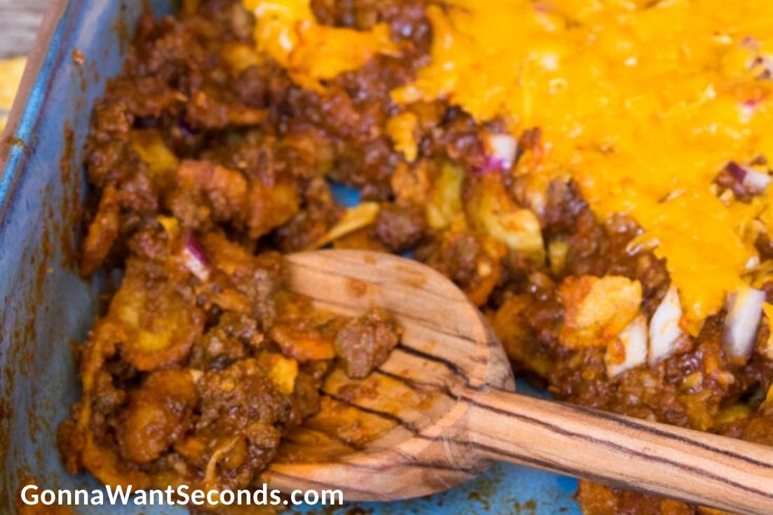 Scooping out a portion of Frito Pie in a casserole dish