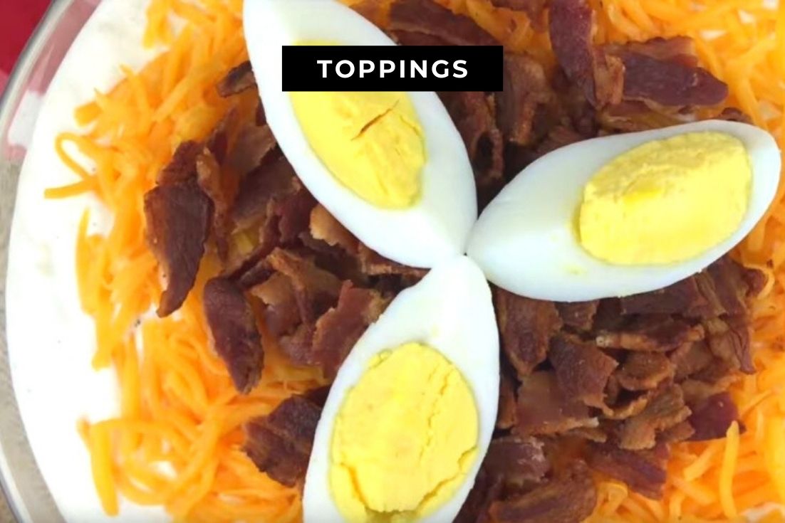 7 Layer Salad garnished with 3 slices of boiled eggs, bacon, and cheese