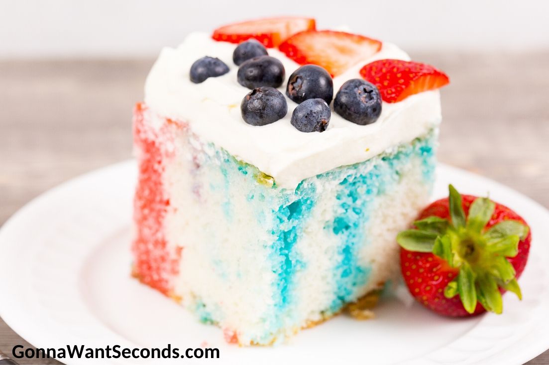 Memorial Day Recipes, A slice of Red White and Blue Poke Cake topped with strawberries and blueberries, on a plate