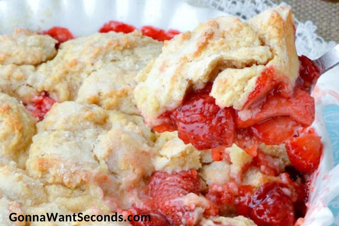 Scooping strawberry cobbler with fresh strawberries