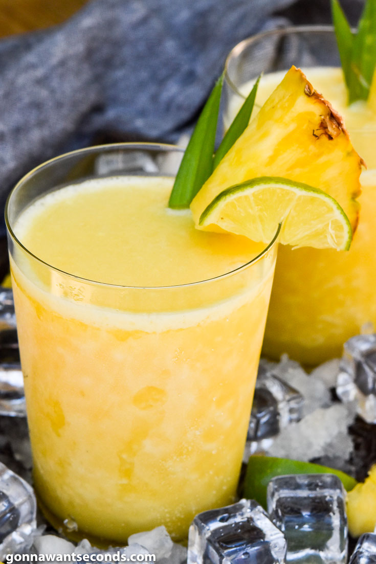 Two glasses of Pineapple Margaritas topped with a slice of pineapple and lime