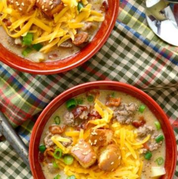 Cheeseburger soup topped with croutons and shredded cheese, in a red bowl