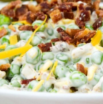 Pea Salad topped with bacon bits and shredded cheese, in a shallow bowl