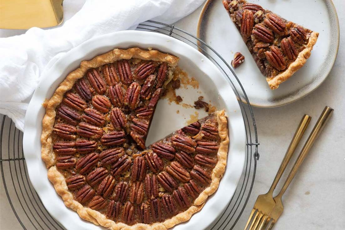 Whole pecan pie crust showing, a slice taken out
