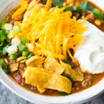 Taco Soup topped with a dollop of sour cream, shredded cheese, and corn chips