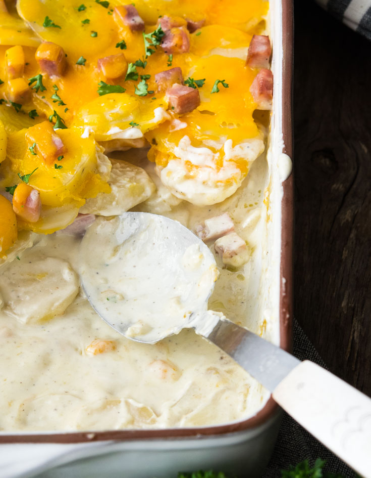 Half casserole of Cheesy scalloped potatoes and ham, with a spoon