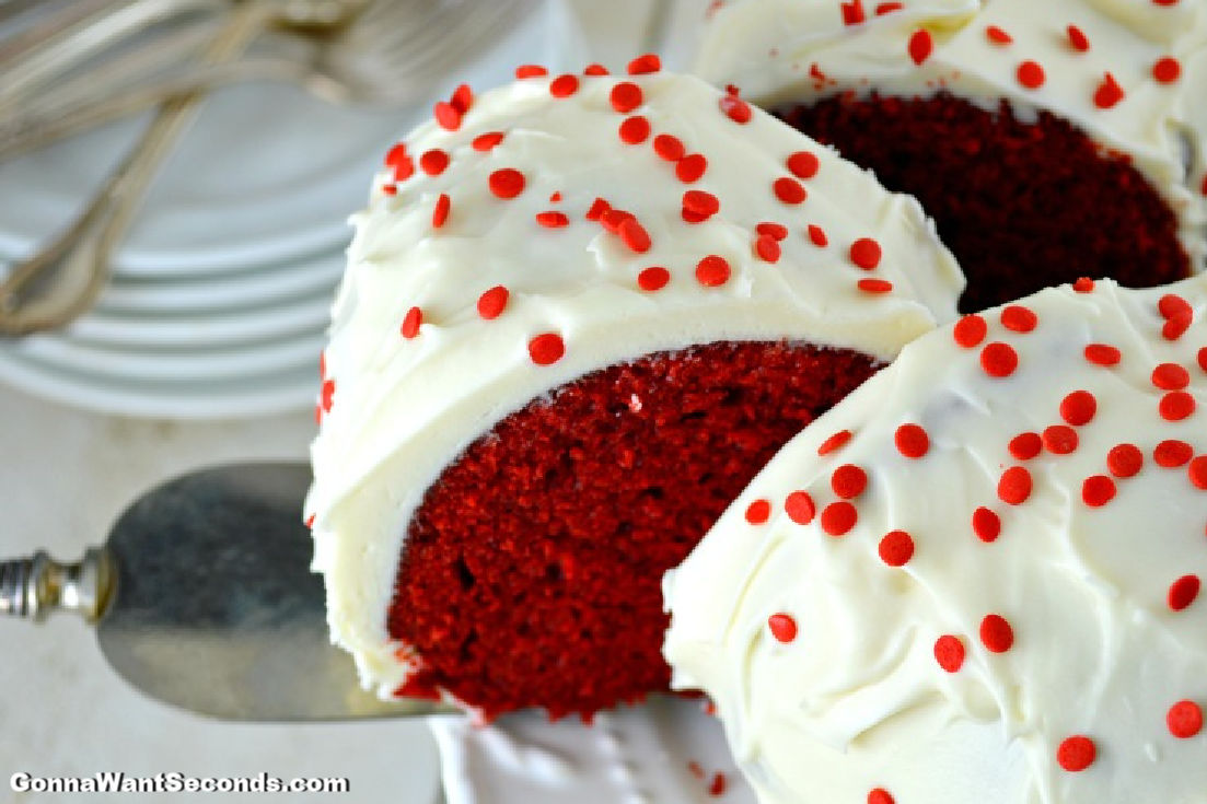 Slicing red velvet bundt cake with cream cheese frosting