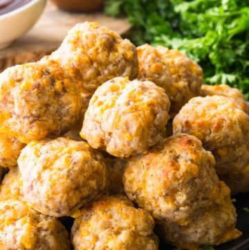 A pile of Bisquick Sausage Balls on a plate with dipping sauces on the side