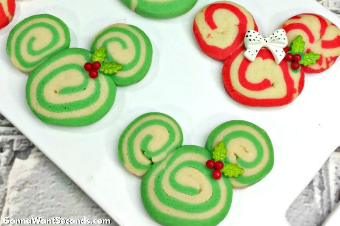 Mickey and Minnie Swirl Cookies on a serving plate with Christmas decor on the side