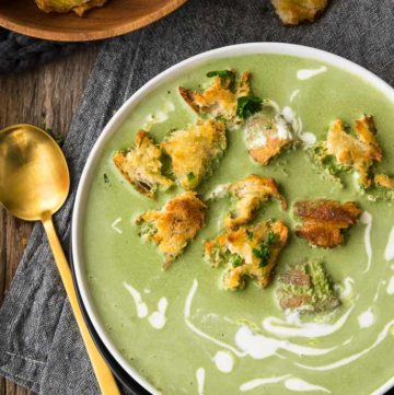 Spinach Soup with croutons and drizzle of heavy cream on top, in a white bowl