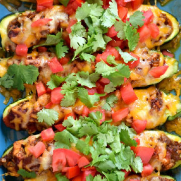 Zucchini Enchilada Boats topped with chopped tomatoes in a casserole dish