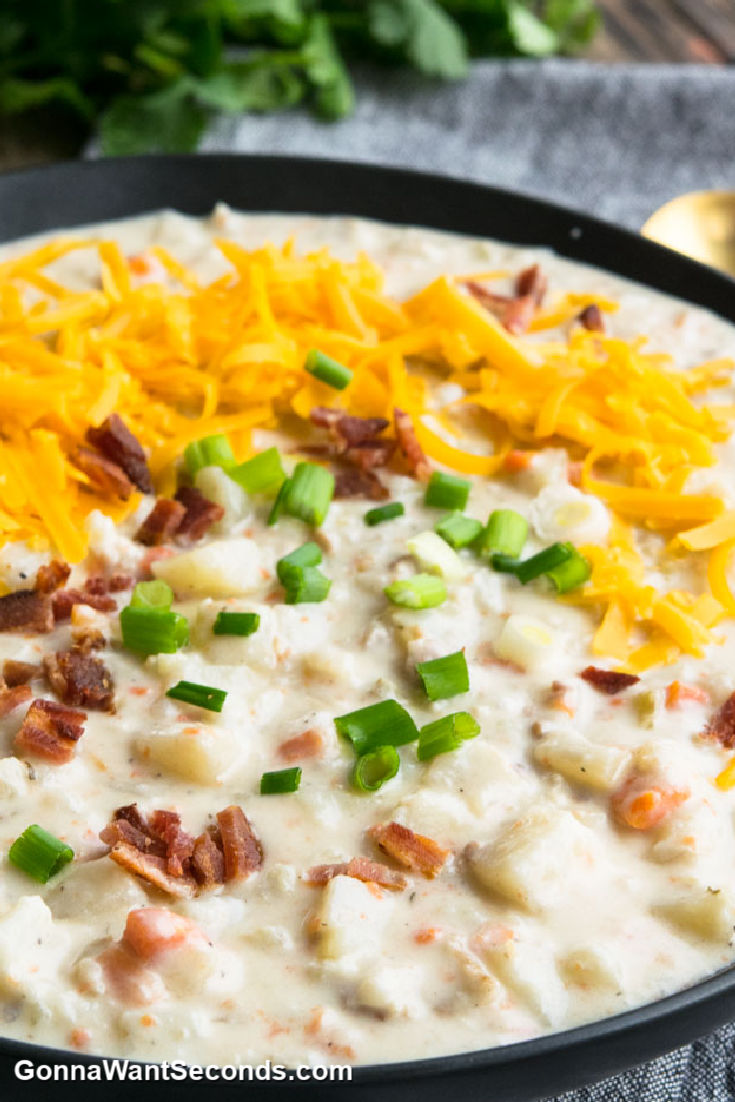 slow cooker potato soup with grated cheese, bacon bits, and green onions on top