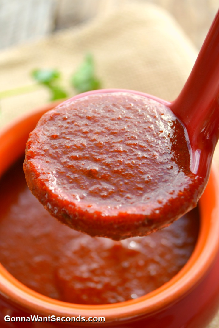 a ladle scooping enchilada sauce from a bowl