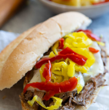 crockpot Italian beef sandwiches, topped with pepperoncini and extra Giardiniera, close up