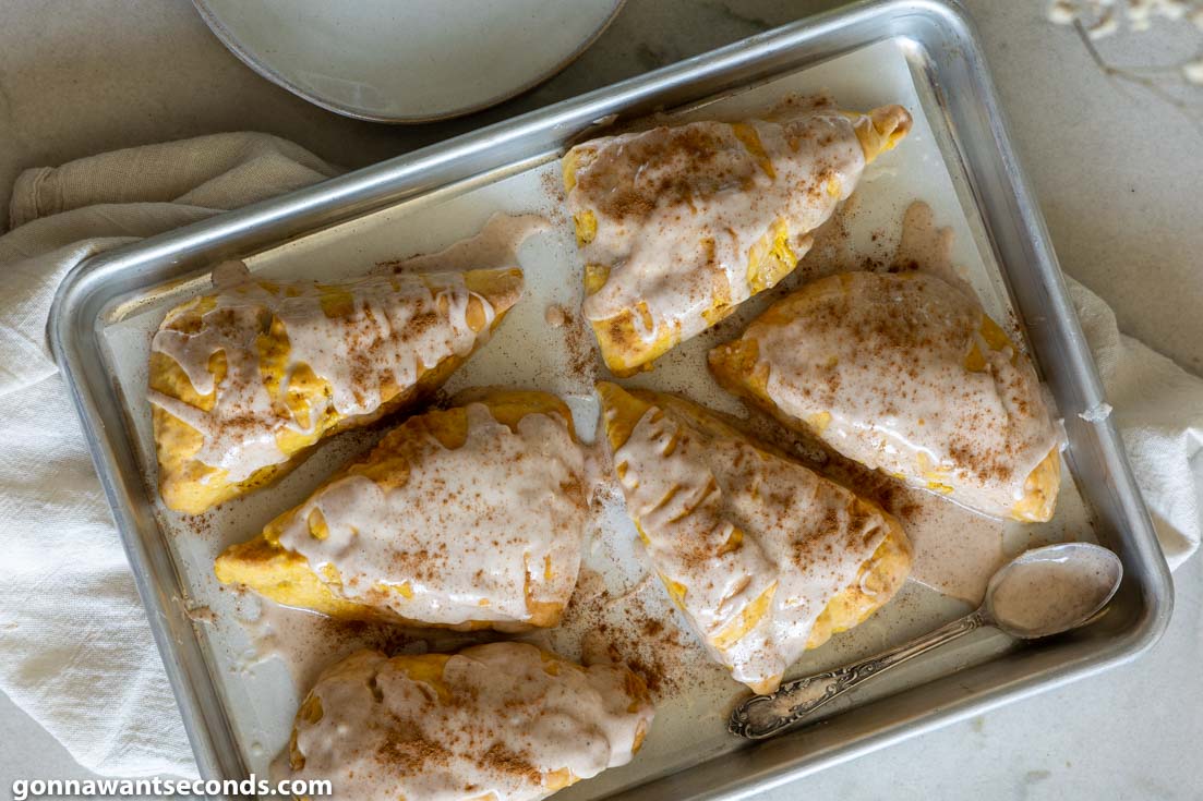 pumpkin scones with spiced glaze on a baking sheet, top shot
