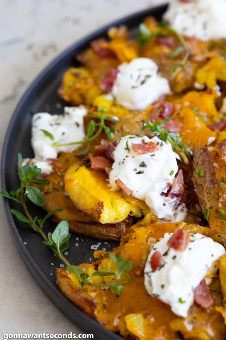 loaded smashed potatoes with sour cream and bacon, on a plate